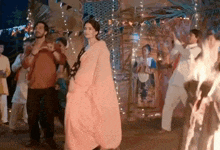 a woman in a pink dress is dancing with a man in a red shirt .