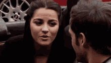 a man and a woman are looking at each other with a wheel in the background