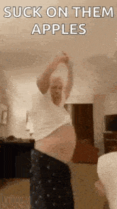 a man with a very large belly is dancing in a living room while a woman watches .
