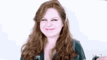 a woman with long red hair is smiling and making a face .