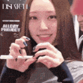 a woman is holding a cell phone in front of a sign that says dispatch