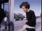 a man in a black sweater is standing in front of a door