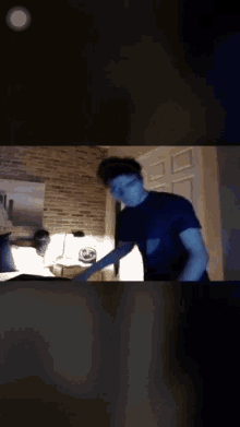 a man in a black shirt is standing in a dark bedroom