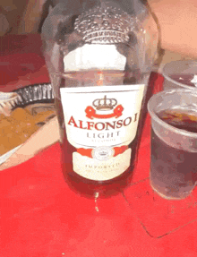 a bottle of alfonso light sits next to a cup