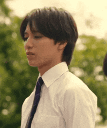 a man in a white shirt and purple tie looks to the side