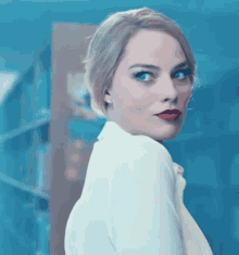 a woman with blonde hair and red lipstick is looking over her shoulder
