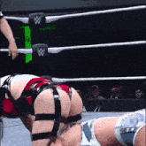 a woman is kneeling down in a wrestling ring with a referee pointing at her .
