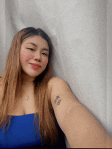 a woman in a blue top has a tattoo on her arm that says safe
