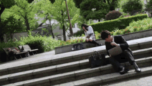 a man sits on a set of stairs while a girl sits on a bench