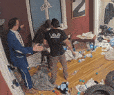 a man in a black shirt with the word vibe on the back is standing in a messy room