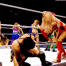 a group of women are wrestling in a ring and one of them is kneeling down on the ground .