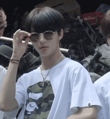 a young man wearing sunglasses and a white t-shirt with a camouflage print