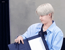 a man in a blue shirt is holding a black folder
