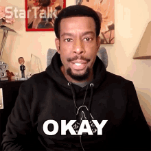 a man wearing a black hoodie that says okay on it