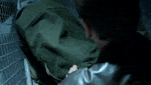 a man is behind a chain link fence with his head down