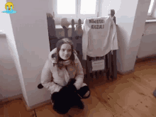 a girl is kneeling in front of a sign that says ' kowinski angzuli '
