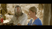 a man with a beard sits next to a woman in a blue shirt