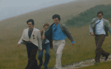 a group of men are walking down a grassy hillside