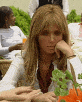 a woman sits at a table with her hand on her face