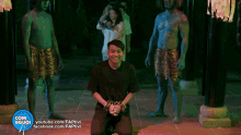 a man in handcuffs is kneeling in front of a group of green and blue men with com người written on the bottom
