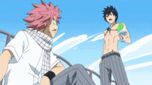 a man with a scarf around his neck stands next to another man without a shirt