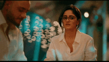 a woman wearing glasses and a white shirt stands next to a man in a white shirt