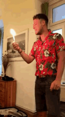 a man in a hawaiian shirt is holding a candle