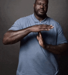 a man in a blue shirt is making a stop gesture