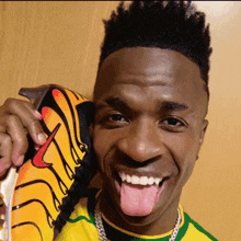 a man wearing a yellow and green shirt is holding a pair of nike soccer cleats
