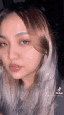 a close up of a woman 's face with a gray hair color .