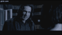 a man in a black shirt is talking to a woman in a dark room .