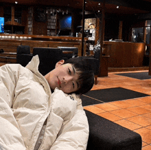 a young man laying on a couch with his head resting on a white blanket