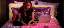 a woman sitting on a bed with a laptop