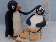 two stuffed penguins are standing next to each other and one is petting the other .