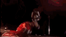 a man is playing a guitar on a stage while another man is kneeling on the floor .