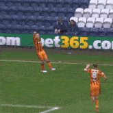 two soccer players are running on a field in front of a sign that says bet365