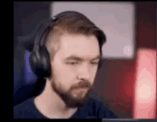 a man with a beard wearing headphones is sitting in front of a laptop computer .