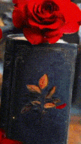 a red rose is sitting on top of a black book