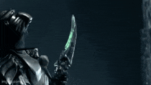 a person is holding a green knife in their hand in a dark room .