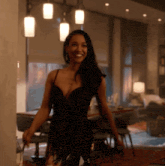 a woman in a black dress smiles in a room