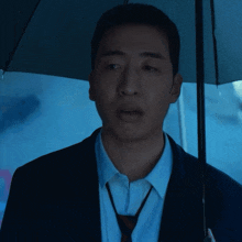 a man in a suit and tie holds an umbrella with the letter o on it