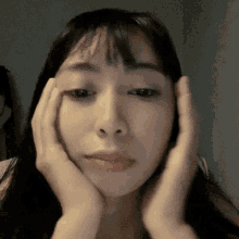 a woman holds her hands to her face and looks at the camera