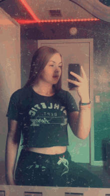 a girl taking a picture of herself in a mirror wearing a crop top that says jht