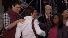 a man in a white shirt is hugging another man in a maroon vest