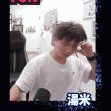 a man wearing glasses and a white shirt with chinese writing on the bottom