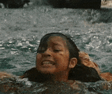 a young girl is swimming in a pool with a shark behind her .