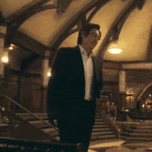 a man in a suit is walking down stairs holding a glass of whiskey