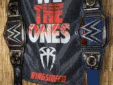 two wrestling belts are hanging on a banner that says the ones ringsideed