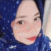 a close up of a woman wearing a hijab with butterflies on her face .
