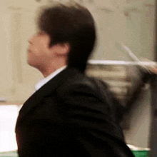 a man in a suit and tie is holding a pair of scissors while walking .